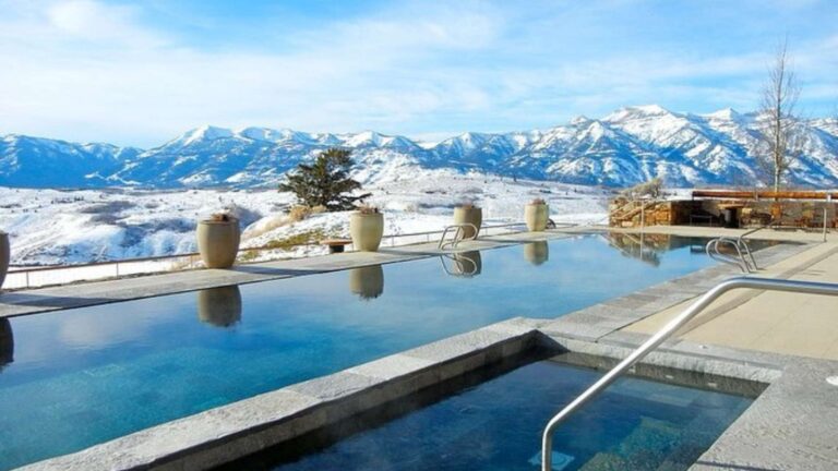 Snowy mountains behind a serene outdoor pool.